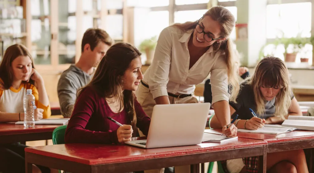 Behavior plan examples - teacher helping student in class. Teacher happy to help student
