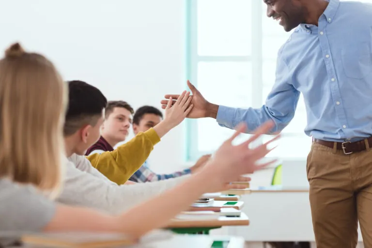 How to write a Behavior Intervention Plan teacher shakes hands with first row of students